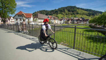 Trachtenmädchen mit Bollen Hut fährt Fahrrad