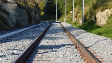 Bild von Bahngleisen zwischen Felsen und Bewuchs