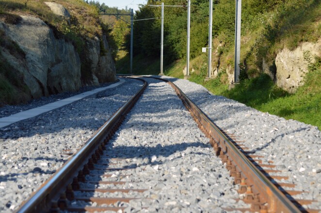 Bild von Bahngleisen zwischen Felsen und Bewuchs
