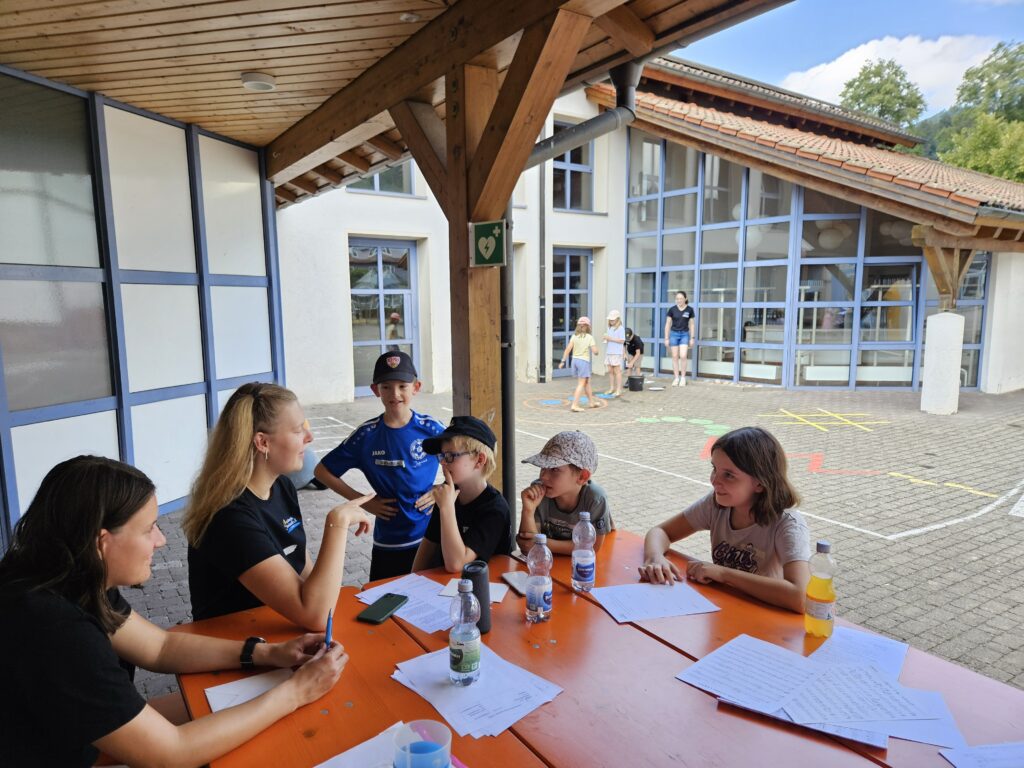Bild von Kindern an einem Tisch mit einem Betreuer