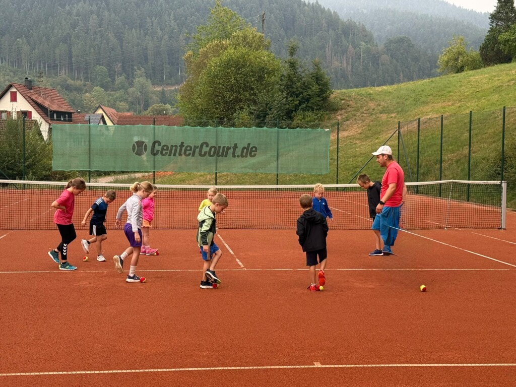 Bild von Kinder mit Betreuer, die mit Tennisbällen auf dem Tennisplatz Fußball spielen