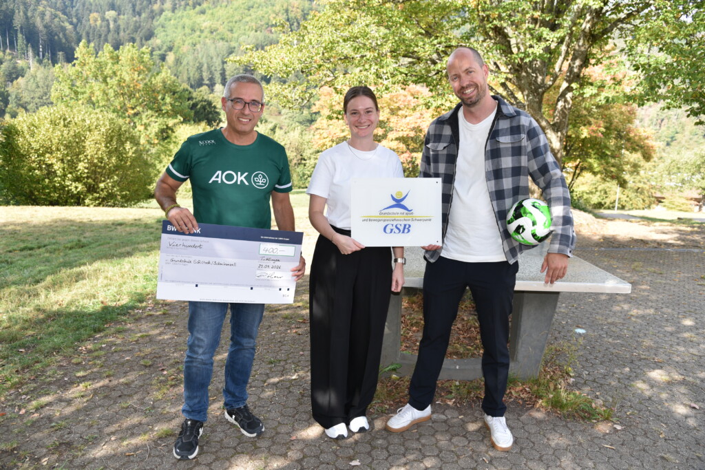 Bild von 3 Erwachsenen mit Scheck und Ball